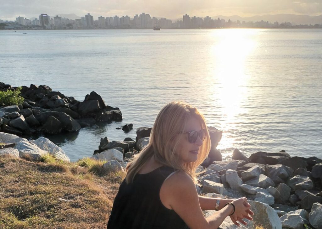  Uma foto da autora, em um momento de reflexão e paz, talvez em um ambiente natural. A foto é pessoal e genuína.